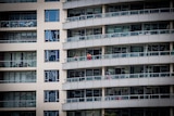 Two people stand on the balcony of an inner city apartment building.