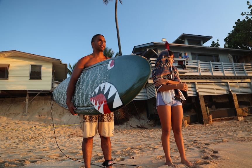 Two people stand on the beach.