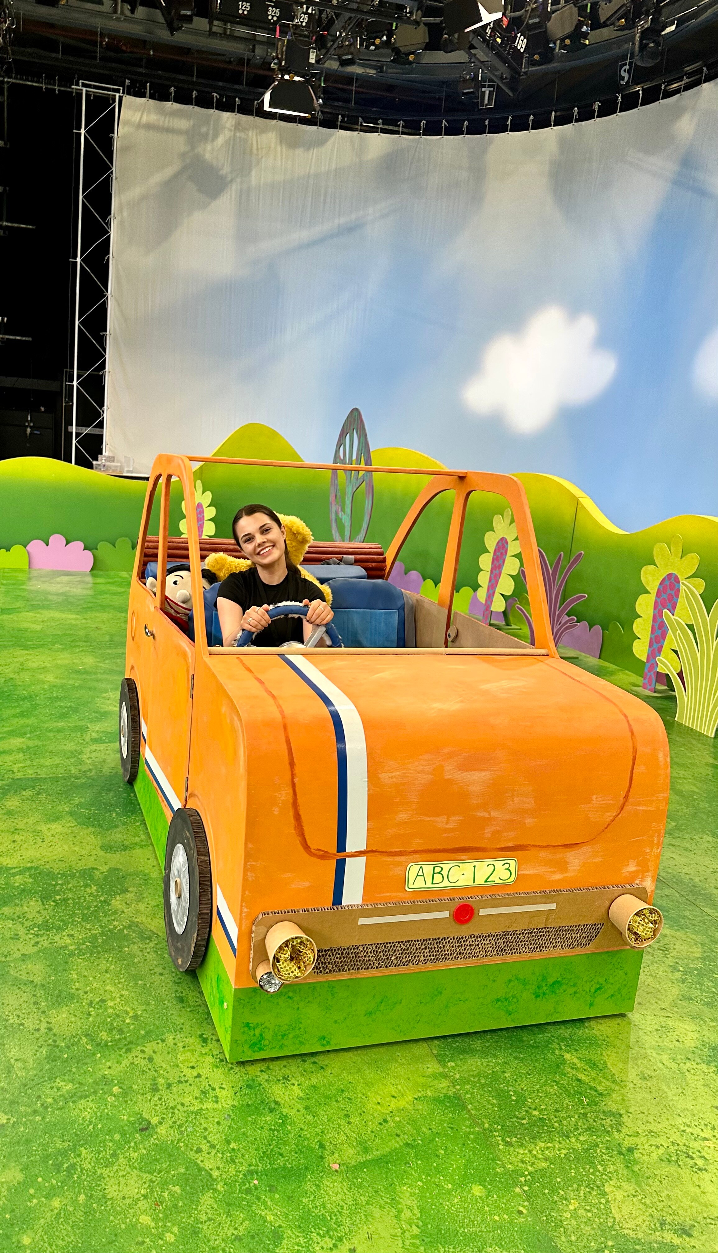 person in yellow prop car on a TV set