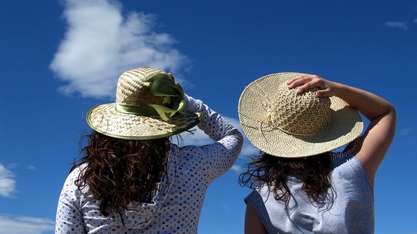 Women holding their hats.