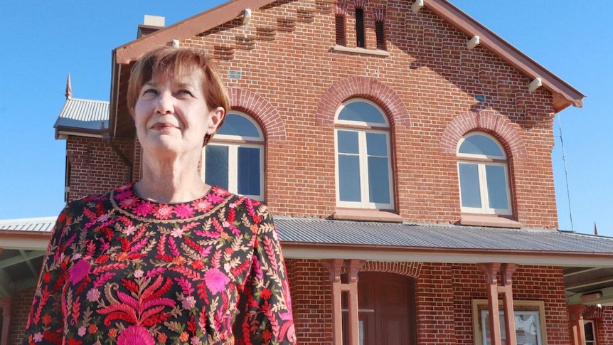 A woman standing in front of an old building.