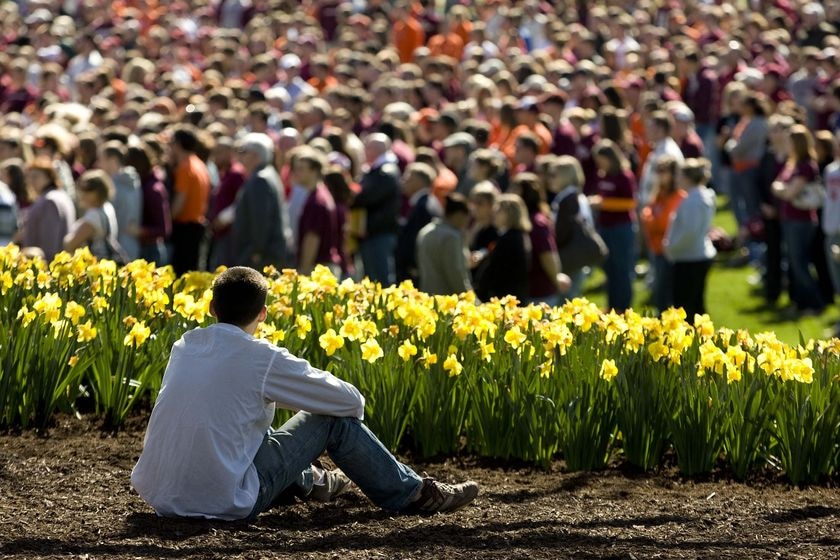 A Virginia Tech student sits overlooking the crowd during a memorial service