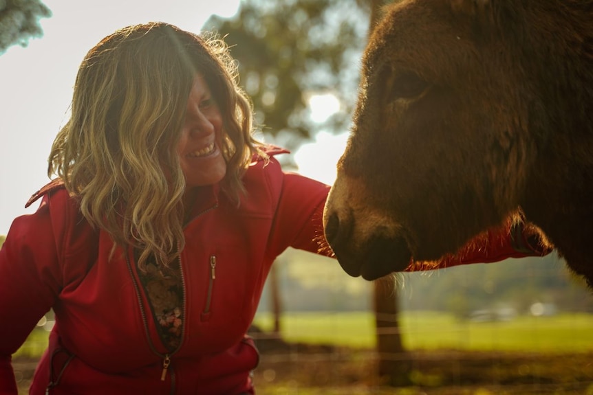 happy woman pats a donkey