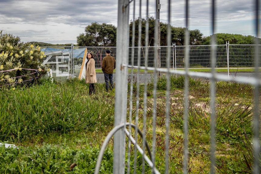 A woman unlocking a metal fence
