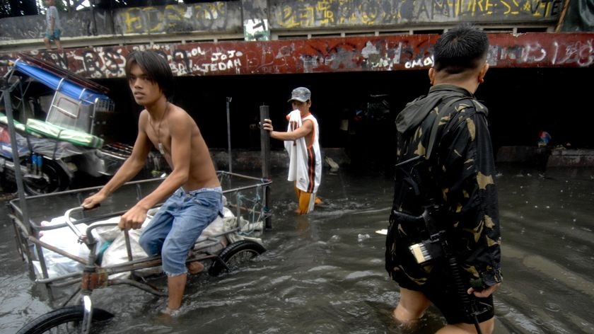 A man rides a bicycle through flood waters in the Philippines