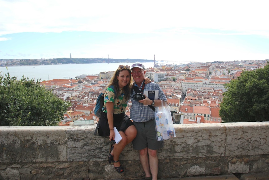 Travel writer Pippa Whishaw and her father Michael pose for a holiday photo on a wall above a southern European port city.