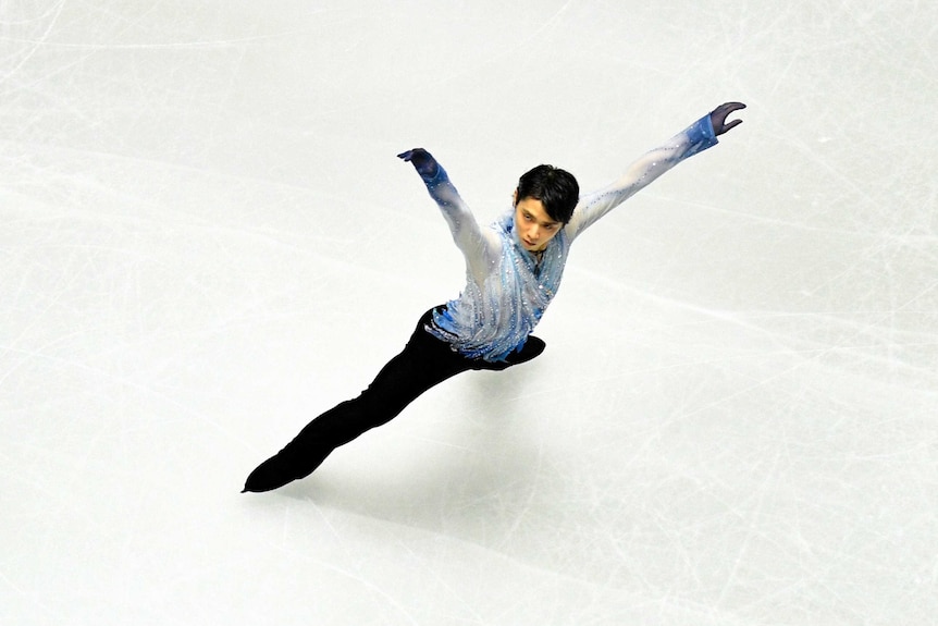 An overhead photograph of Yuzuru Hanyu striking a star shape of white ice