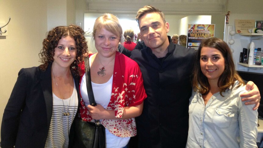 Susan Heymann stands with Robbie Williams and two others backstage.