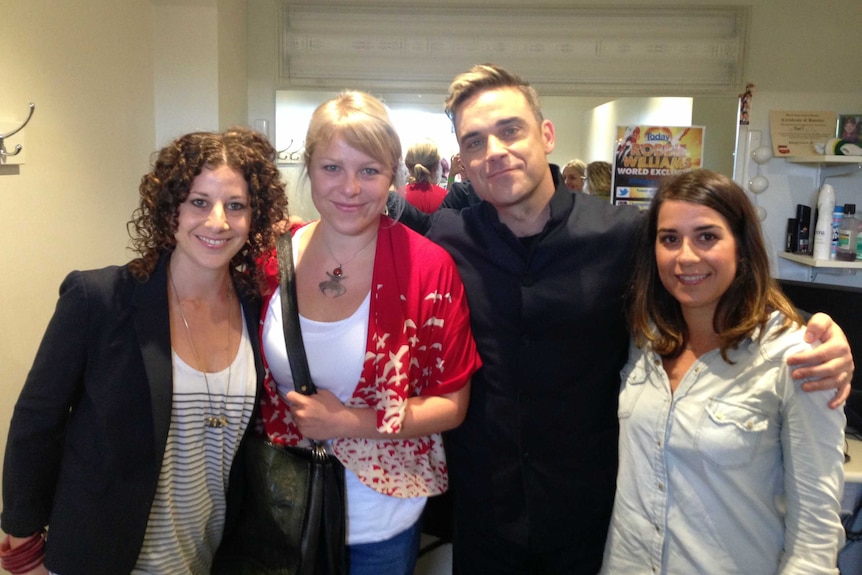 Susan Heymann stands with Robbie Williams and two others backstage.