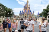 People wearing masks in front of Disney World's Cinderella Castle.