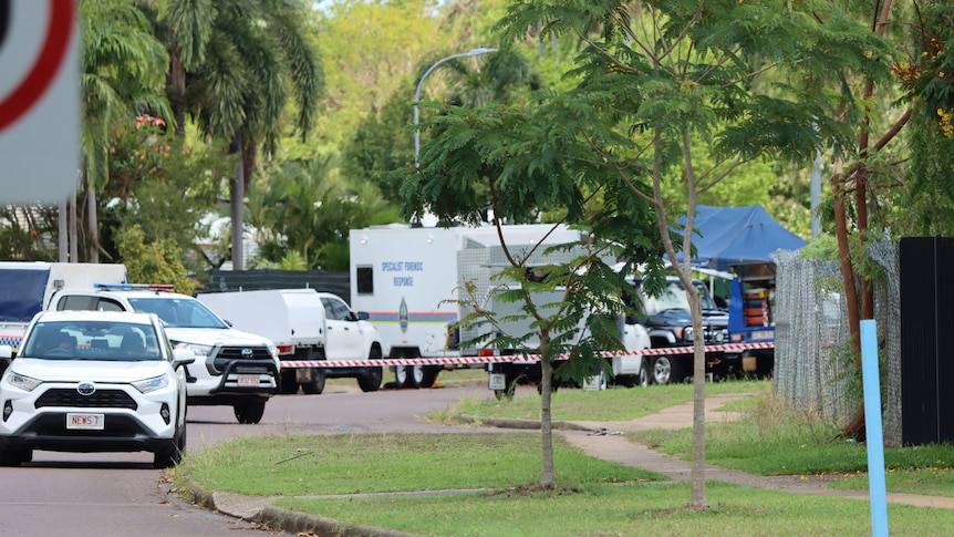 Several NT Police vehicles parked in a suburban street, with police tape in the background.