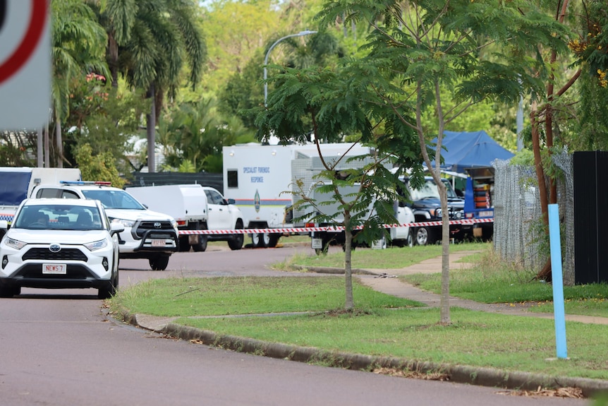 Several NT Police vehicles parked in a suburban street, with police tape in the background.