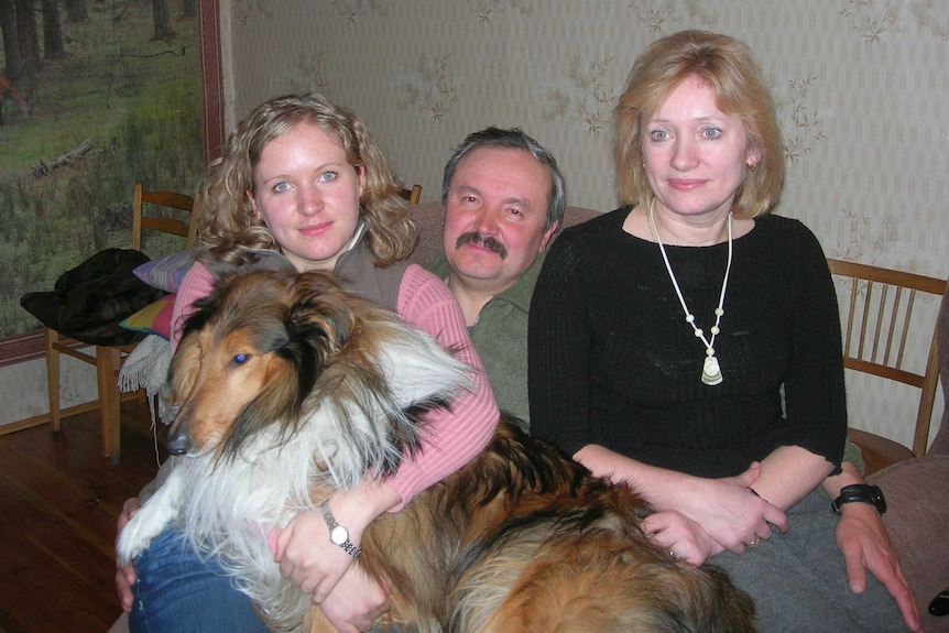 Svetlana Zhukova poses next to her father (left) and mother (right) with the family dog on her lap