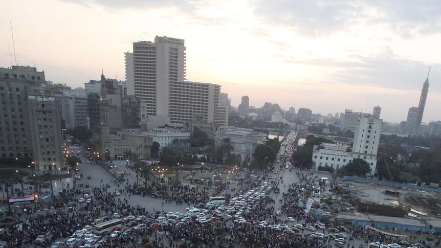 Traffic passes through a crowded Tahrir Square