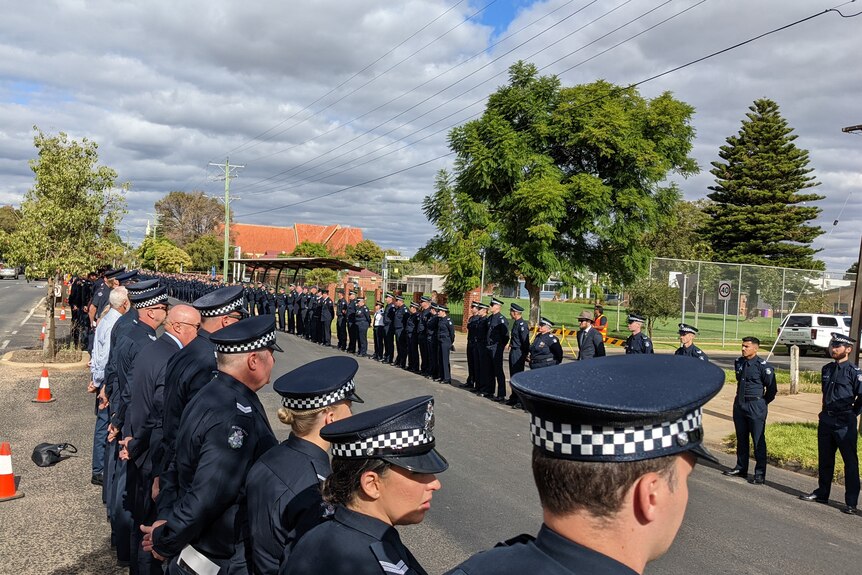 Police form a guard of honour at a funeral for a colleague.