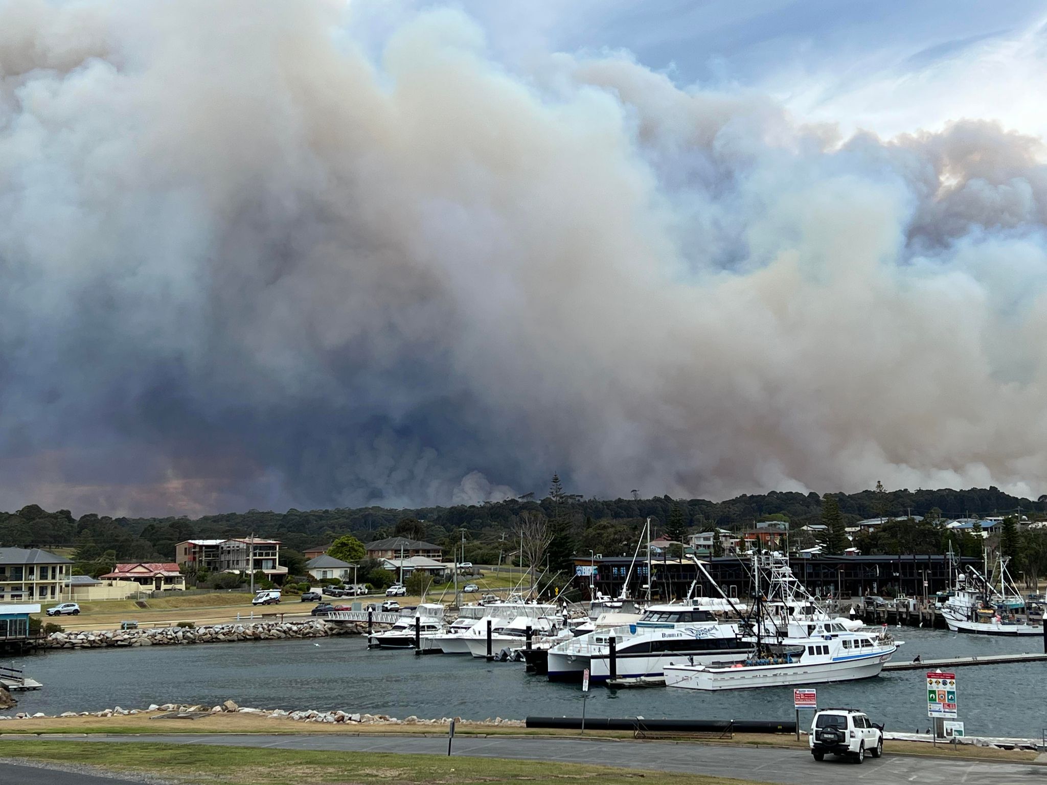 Smoke plumes into sky in front of a marina