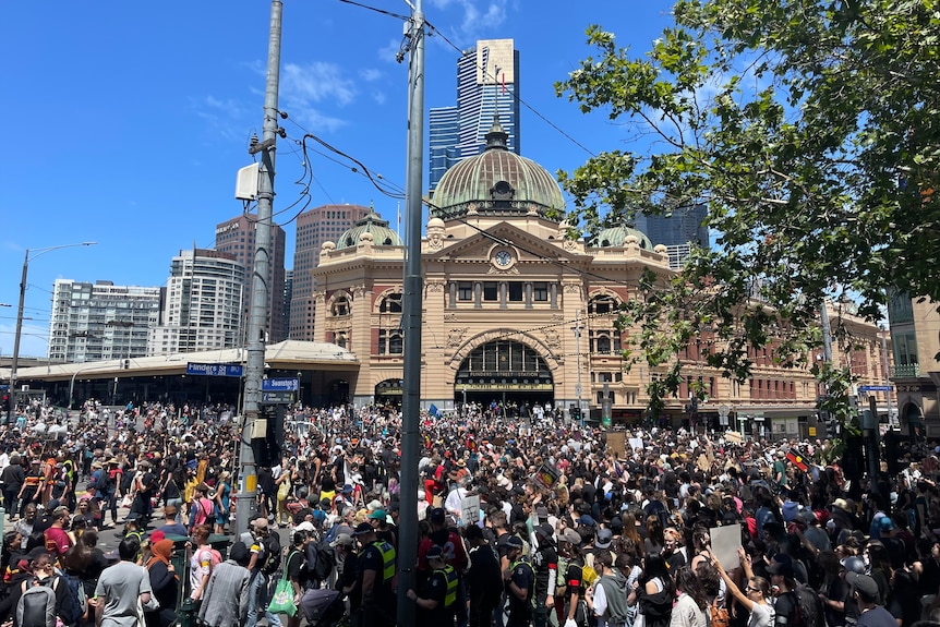 A large crowd of people outside Flinders Street Station in Melbourne.