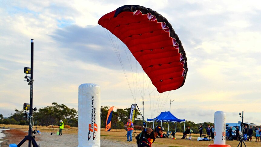 A man flies a skydiving canopy near the ground in a competition