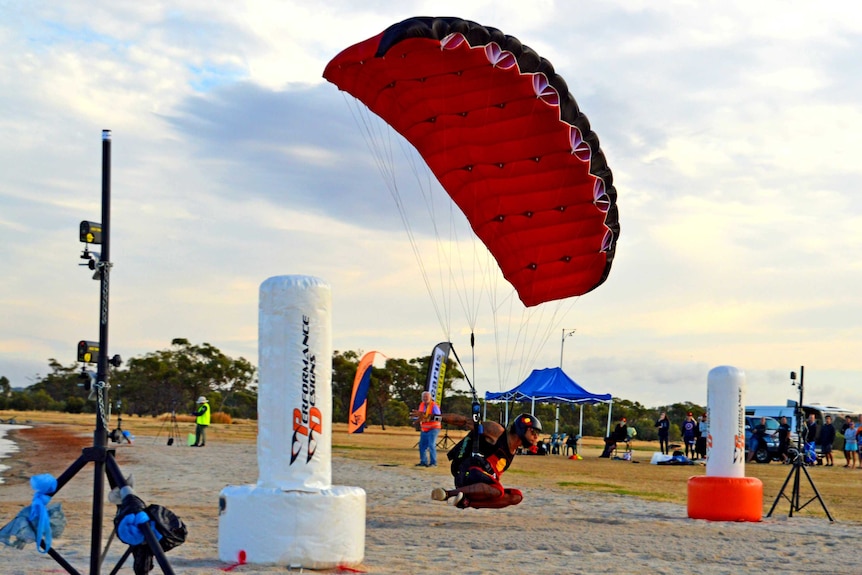 A man flies a skydiving canopy near the ground in a competition