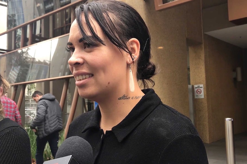 A young woman with dark hair talks to media outside the Melbourne Coroners Court.