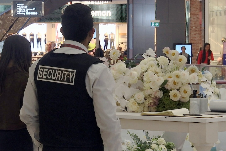 security guard stands over floral tributes inside westfiled bondi junction on 200424