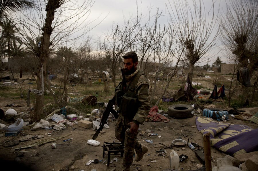 A man in military uniform walking in ruins.