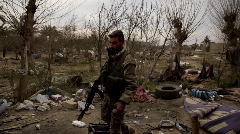 A man in military uniform walking in ruins.