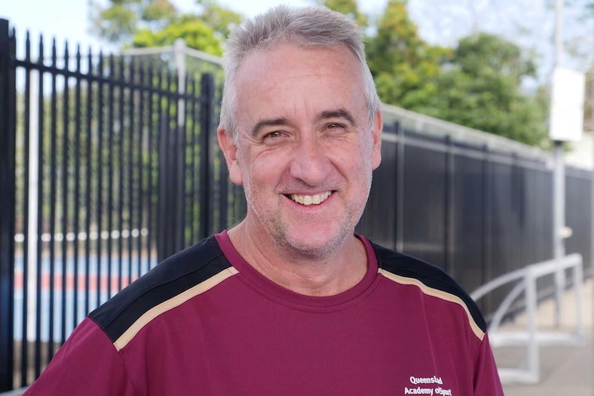 Man in maroon shirt smiling.