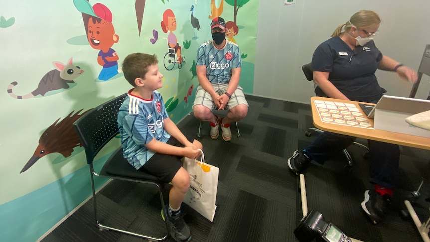 A boy, adult and nurse in a vaccination room