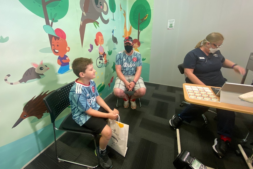 A boy, adult and nurse in a vaccination room