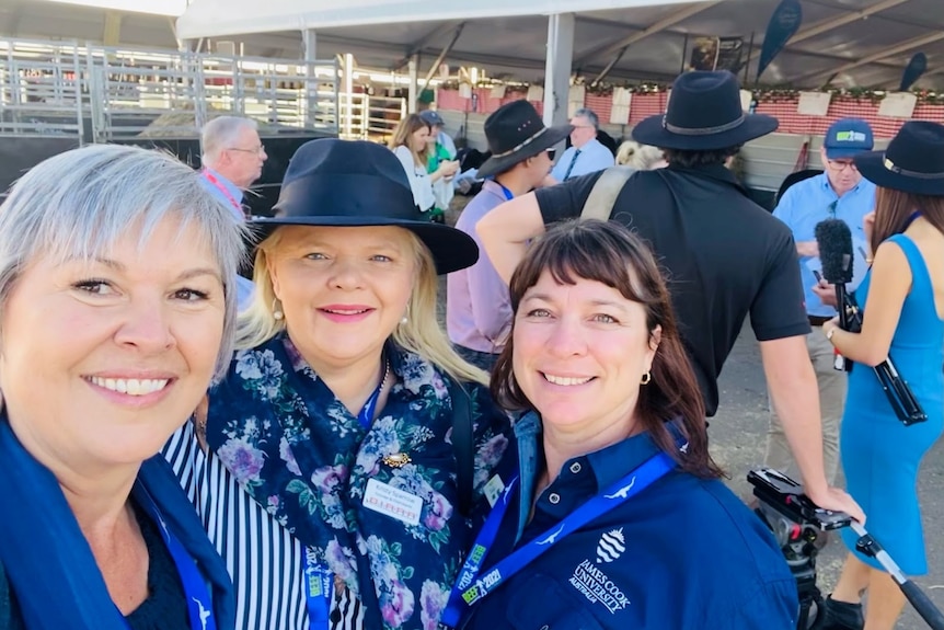 women in blue shirts smile at camera