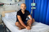 Angelo Romero in hospital sitting on a bed to received his first round of chemotherapy.