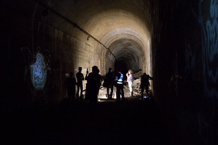 Media tour group examine graffiti in the St James station disused tunnel