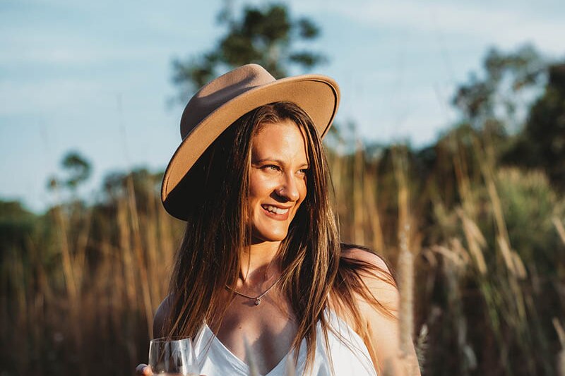 Woman looking to right of frame outdoors with a wine glass.