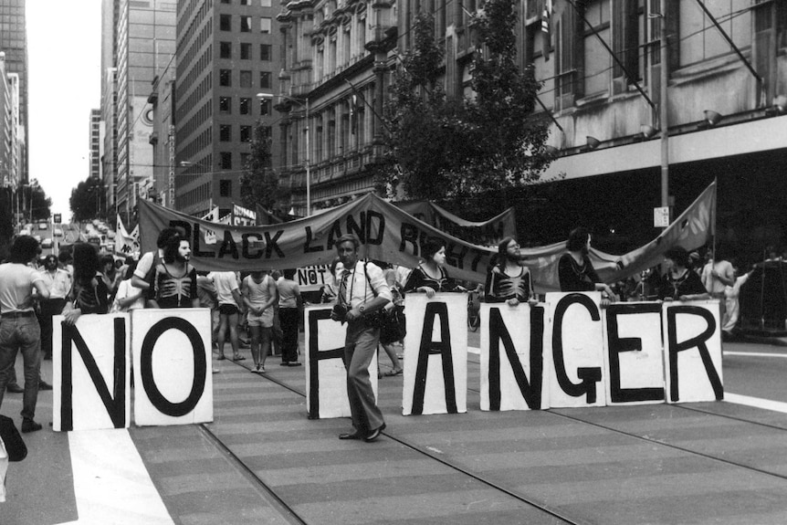 An historical photo of people marching through a street holding banners.