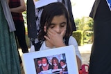 A young Yazidi refugee in Wagga holds up a photo of women captives at rally after latest massacre in Syria
