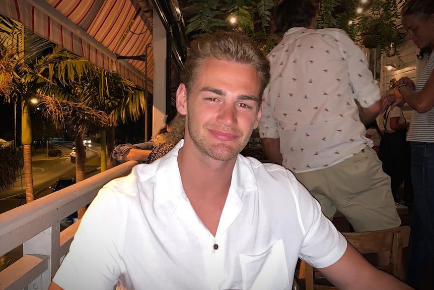 A young man wearing a white shirt at a bar scene