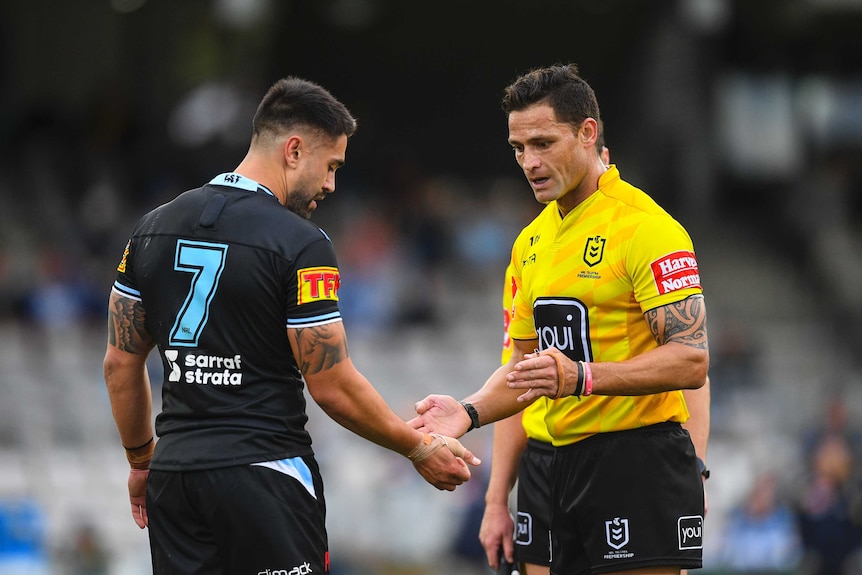 A Cronulla Sharks NRL player shows his right arm to a referee following an alleged biting incident.