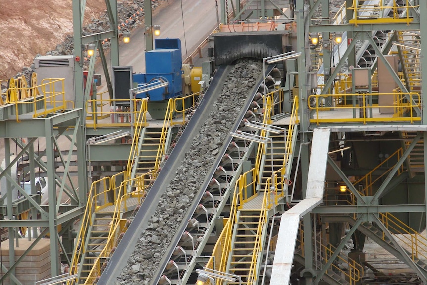 Ore being moved down a conveyer belt at an outside mine.