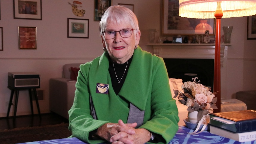 Ms Davenport sits at her kitchen table. Pictures, including a ceramic Emily's List bust sits behind her.