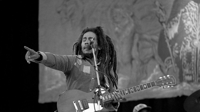 Bob Marley onstage caught pointing to the crowd while holding a guitar.