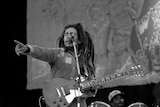 Bob Marley onstage caught pointing to the crowd while holding a guitar.