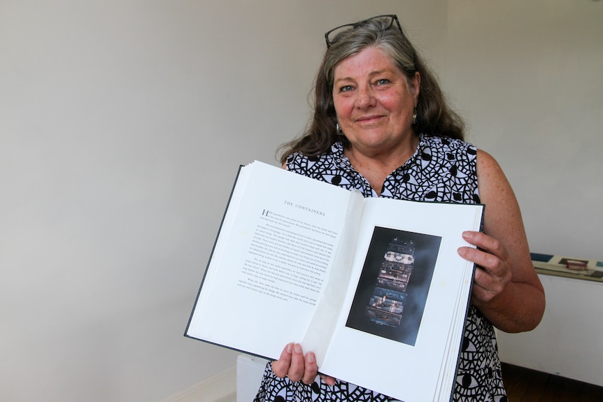 A woman holds a book she made with photographs of familiar objects.