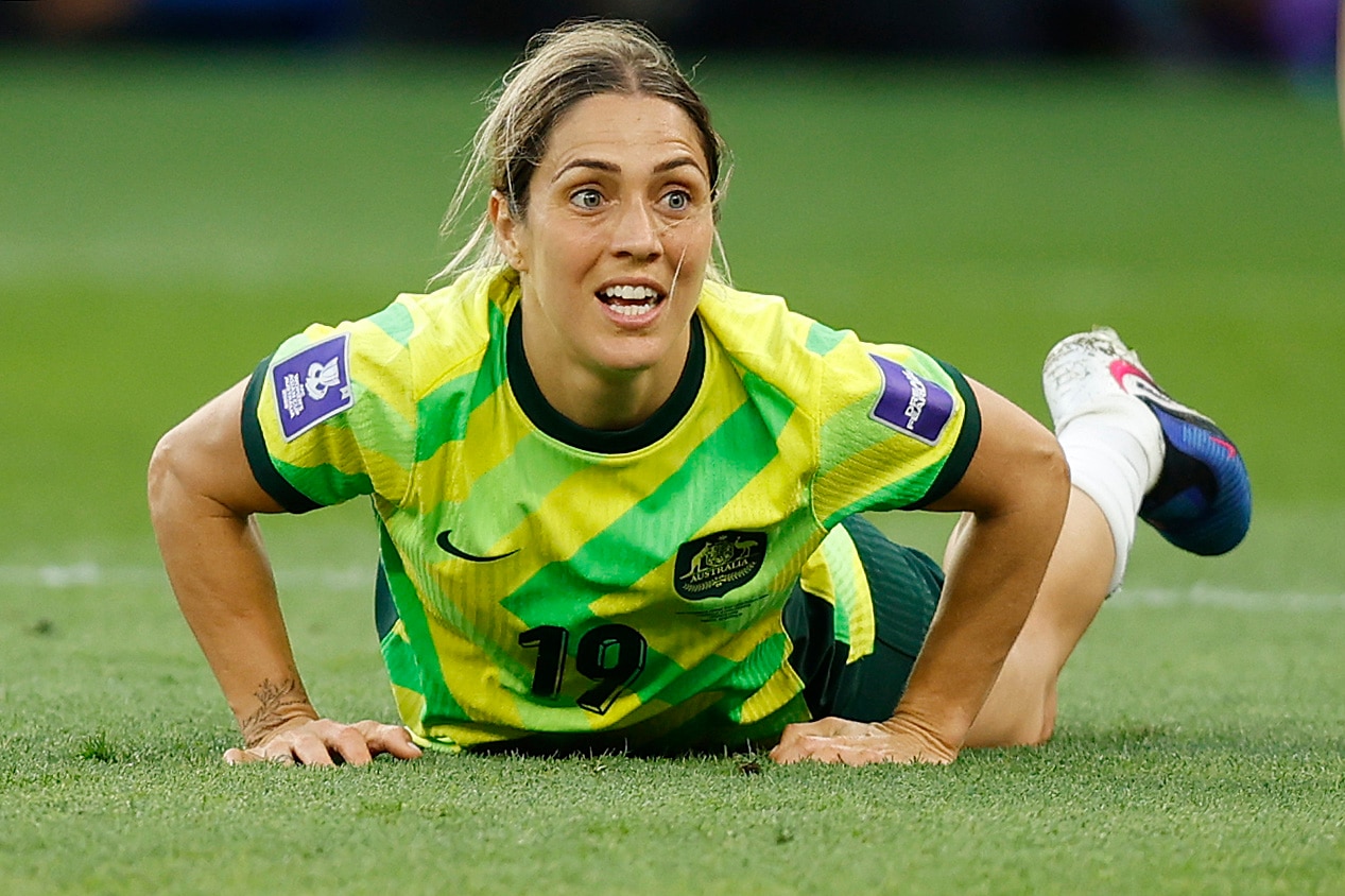 A jogadora do Matildas, Katrina Gorry, está deitada no chão, ela se levanta com uma expressão tensa no rosto