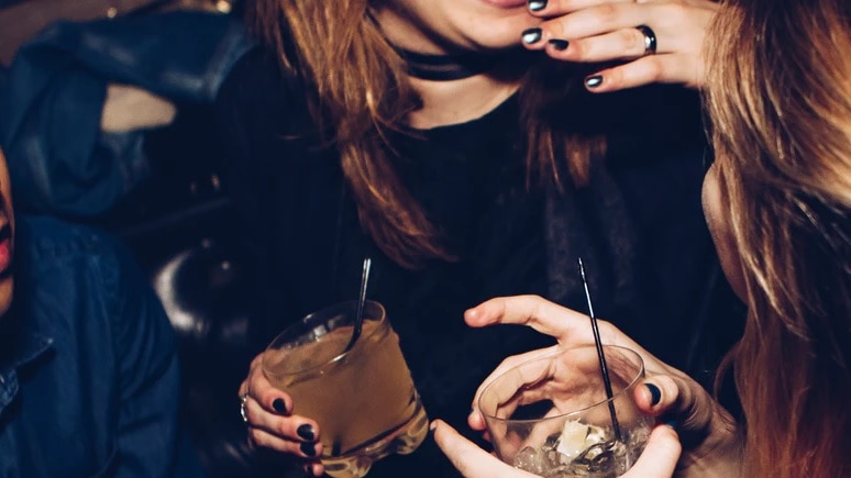 women standing around with two drinks