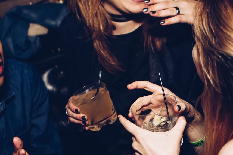 women standing around with two drinks