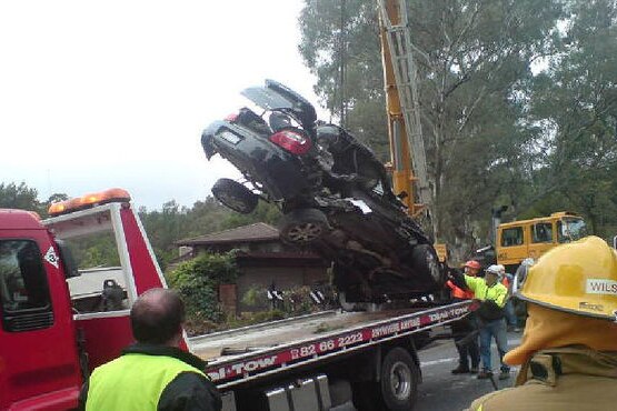 A wrecked car is moved after it was hit by a runaway quarry truck