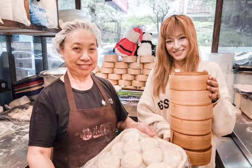 Two ladies are holding steamed dumplings 