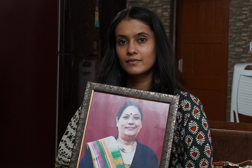 A young Indian woman holding a portrait of her late mother. 