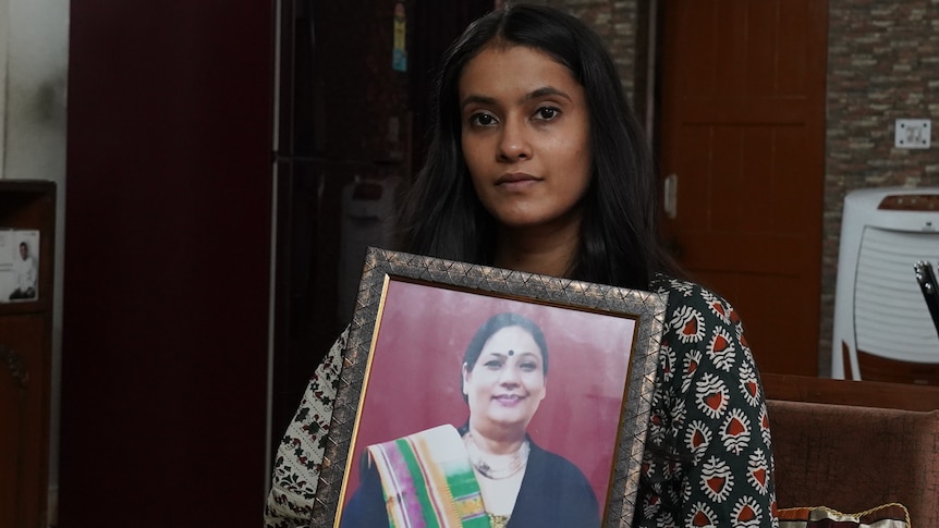 A young Indian woman holding a portrait of her late mother. 